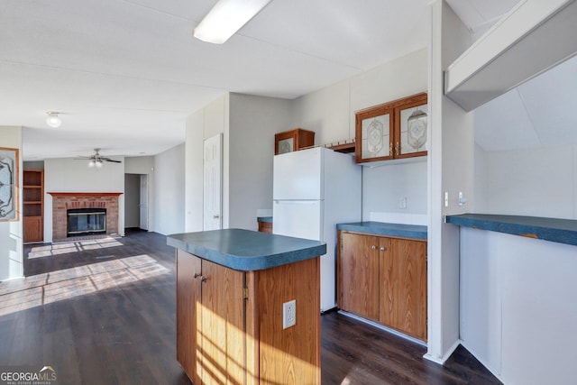 kitchen with white refrigerator, a fireplace, ceiling fan, and dark hardwood / wood-style floors