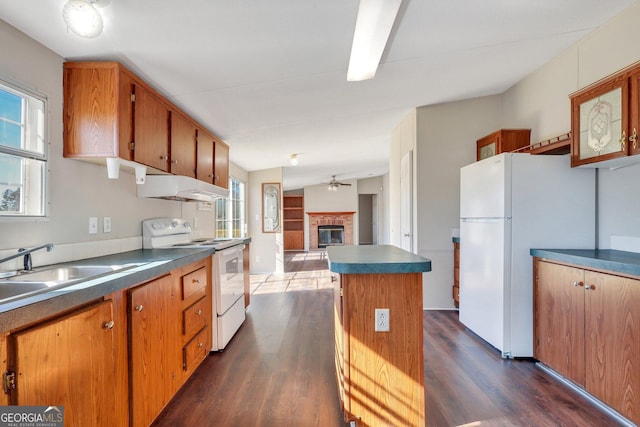 kitchen featuring white appliances, dark hardwood / wood-style floors, a center island, and a fireplace