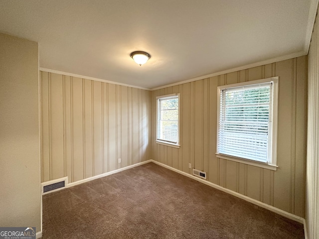 unfurnished room featuring ornamental molding and dark colored carpet