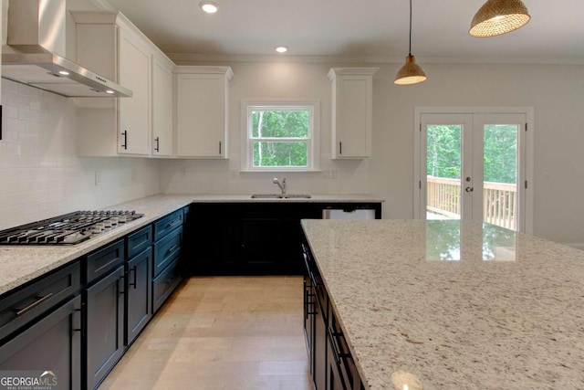 kitchen featuring white cabinets, french doors, decorative light fixtures, and wall chimney exhaust hood