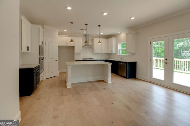 kitchen with stainless steel appliances, light wood-type flooring, a sink, and wall chimney range hood