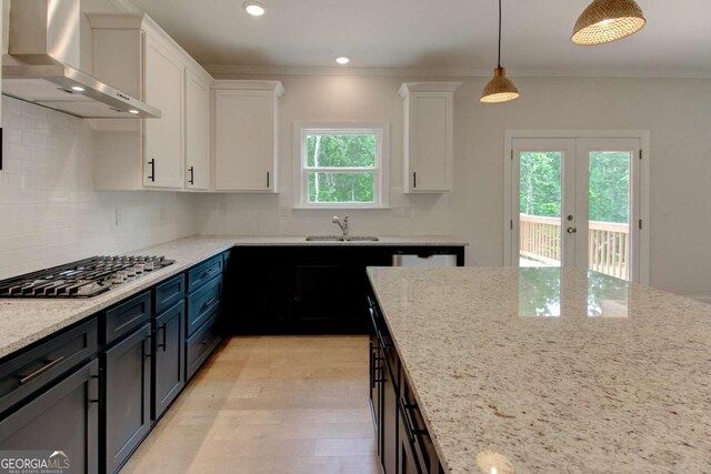 kitchen featuring sink, wall chimney range hood, white cabinetry, and appliances with stainless steel finishes