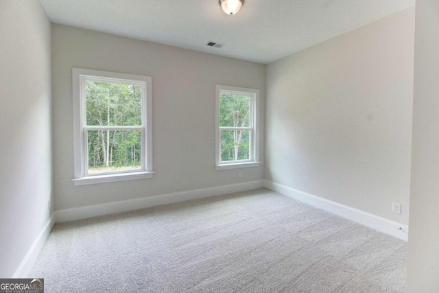 carpeted spare room with visible vents and baseboards