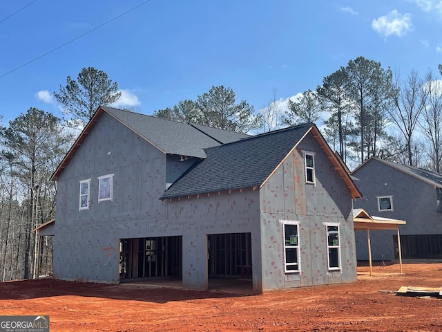 rear view of house with a shingled roof and driveway