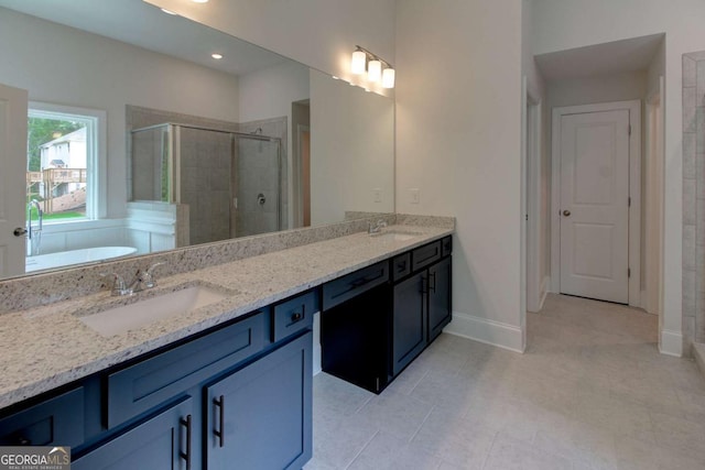 bathroom featuring a sink, a shower stall, baseboards, and double vanity