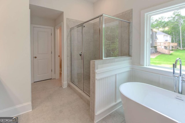 bathroom featuring a freestanding tub, a shower stall, and tile patterned floors