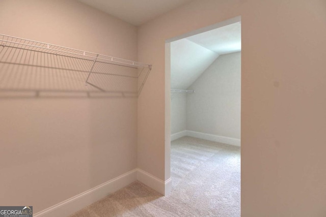 walk in closet with vaulted ceiling and carpet floors