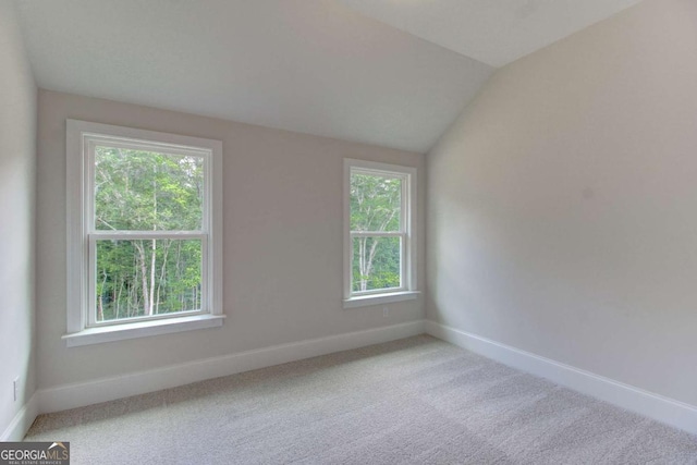 carpeted spare room featuring lofted ceiling and plenty of natural light