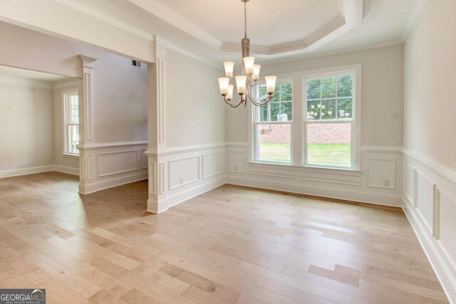 unfurnished living room with light hardwood / wood-style floors, ornamental molding, and a tray ceiling