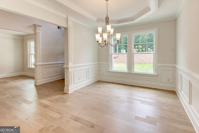 unfurnished dining area featuring light wood-style floors, a raised ceiling, and a healthy amount of sunlight