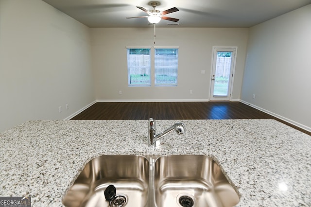 kitchen featuring light stone counters, dark wood-type flooring, ceiling fan, and sink