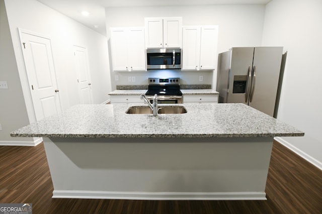 kitchen featuring light stone countertops, a center island with sink, white cabinets, appliances with stainless steel finishes, and sink