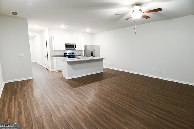 kitchen with a kitchen island with sink, appliances with stainless steel finishes, light stone counters, dark hardwood / wood-style floors, and white cabinets