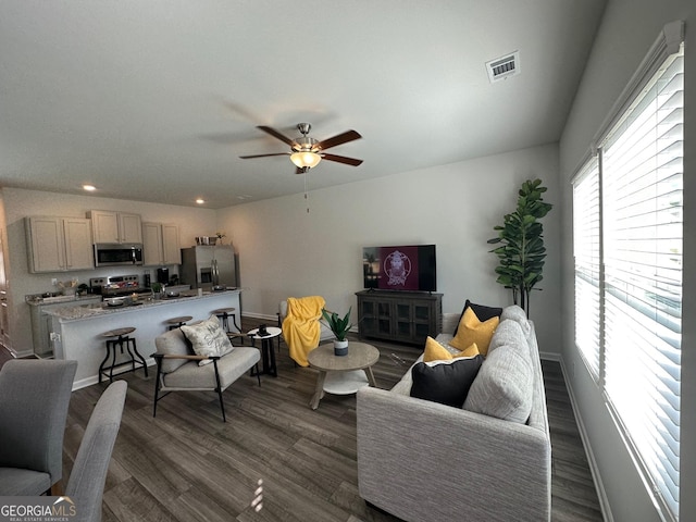 living room with ceiling fan and dark wood-type flooring