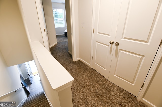 hall featuring dark colored carpet