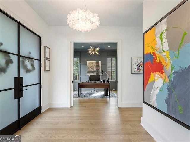 hallway featuring an inviting chandelier and light hardwood / wood-style floors