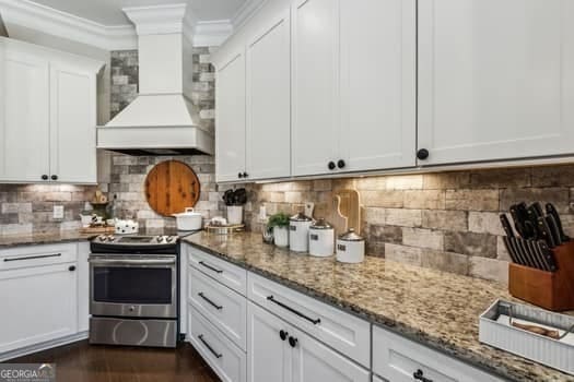 kitchen featuring electric range, white cabinetry, backsplash, and custom range hood