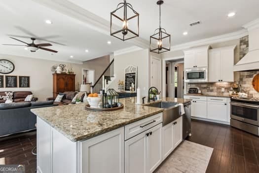 kitchen with stainless steel appliances, a kitchen island with sink, and white cabinets