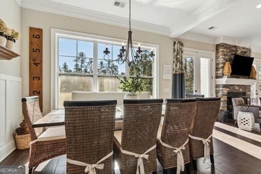 dining area featuring a notable chandelier, dark hardwood / wood-style floors, beamed ceiling, and a fireplace