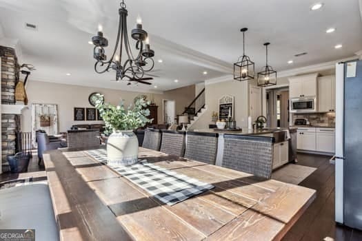 dining room featuring dark hardwood / wood-style flooring, ornamental molding, and a stone fireplace