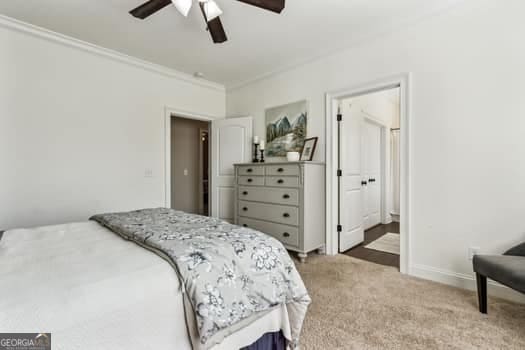 bedroom featuring ensuite bathroom, carpet floors, ceiling fan, and crown molding