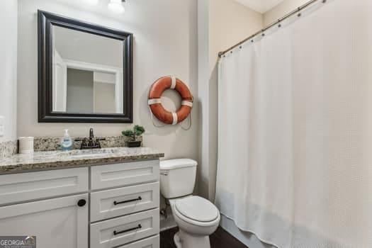 bathroom with a shower with shower curtain, vanity, and toilet