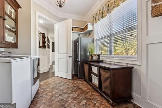 laundry area with separate washer and dryer, crown molding, and a healthy amount of sunlight