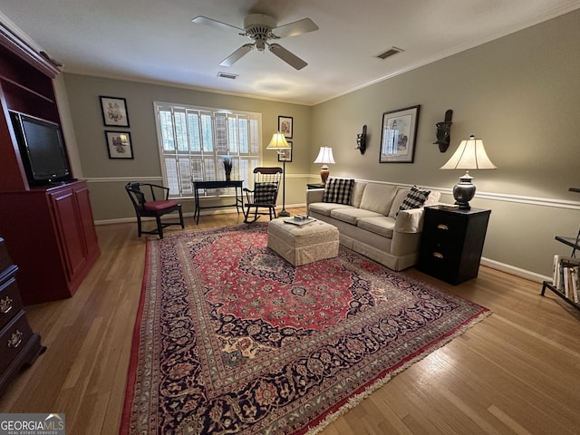 living room with ceiling fan, light wood-type flooring, and ornamental molding