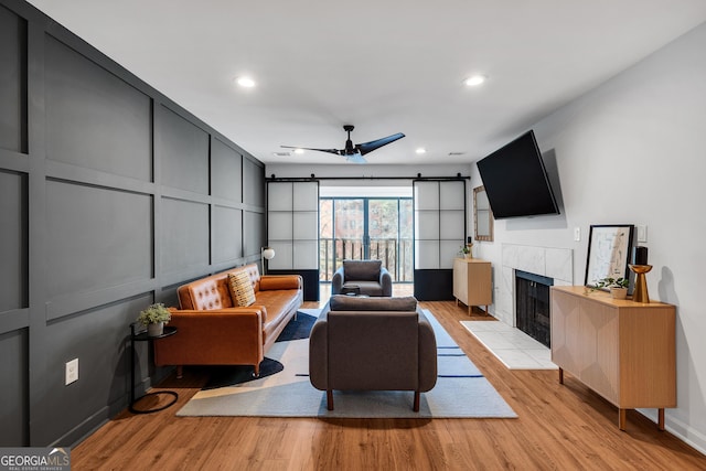 living room featuring a fireplace, ceiling fan, and light hardwood / wood-style floors