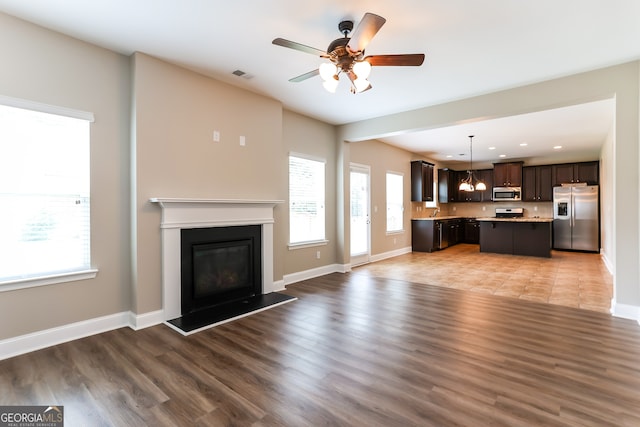 unfurnished living room featuring ceiling fan and hardwood / wood-style floors