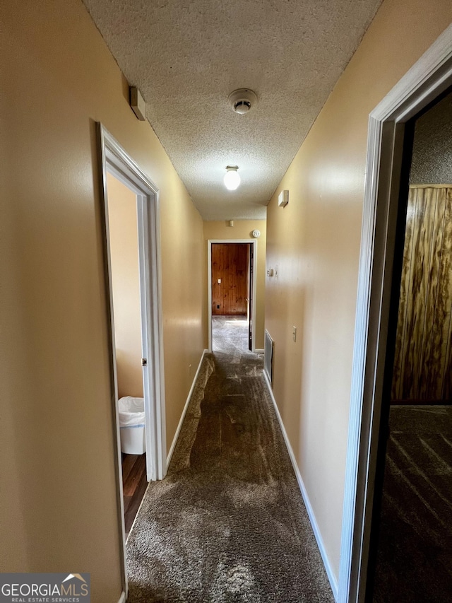 corridor featuring a textured ceiling and carpet