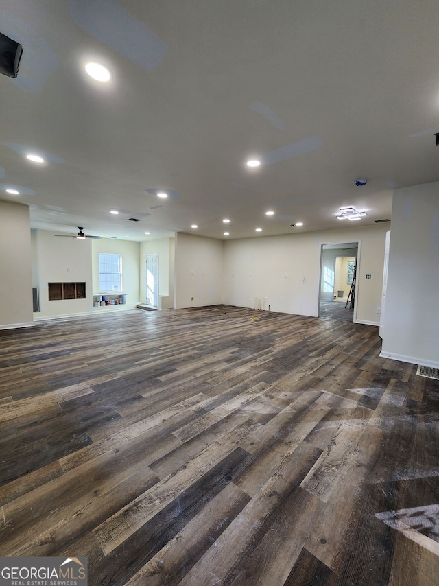 unfurnished living room with plenty of natural light, dark hardwood / wood-style floors, and ceiling fan