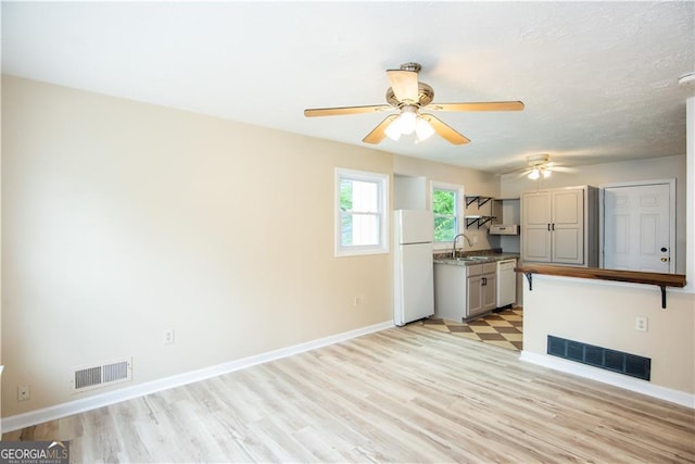 kitchen with sink, white appliances, ceiling fan, and light hardwood / wood-style floors