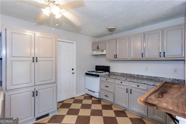 kitchen featuring a textured ceiling, white range with gas cooktop, ceiling fan, and gray cabinets