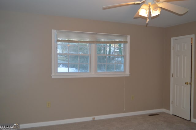 carpeted empty room with ceiling fan, visible vents, and baseboards