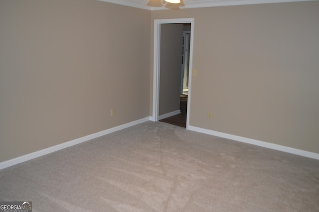 spare room featuring light colored carpet, crown molding, and baseboards