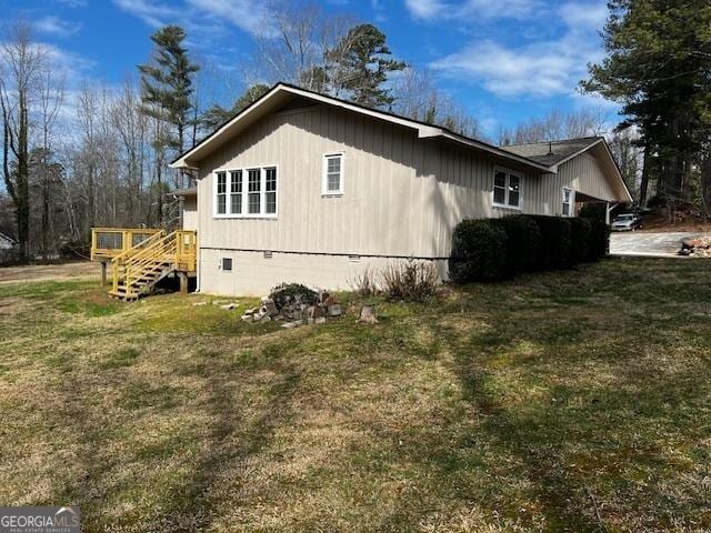 view of side of home with crawl space and a lawn