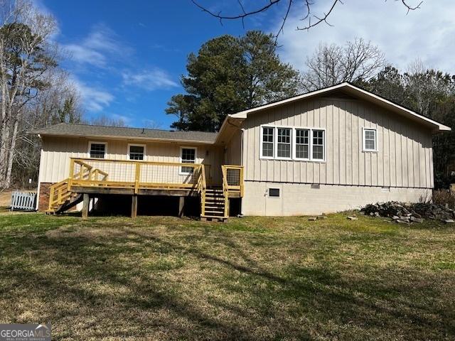 back of house with stairs, crawl space, a wooden deck, and a lawn