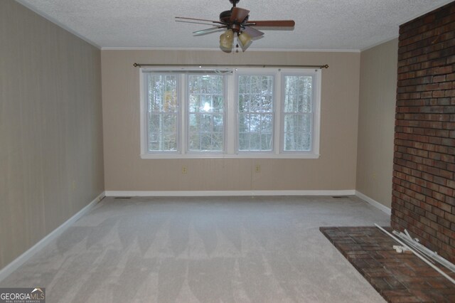 empty room featuring a textured ceiling, ceiling fan, ornamental molding, and light colored carpet