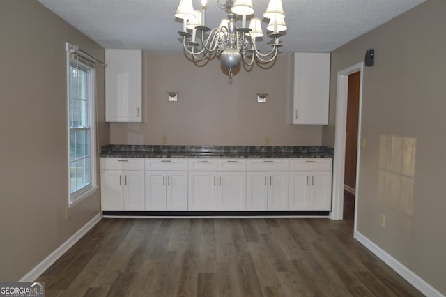 kitchen with plenty of natural light, a textured ceiling, an inviting chandelier, and white cabinets