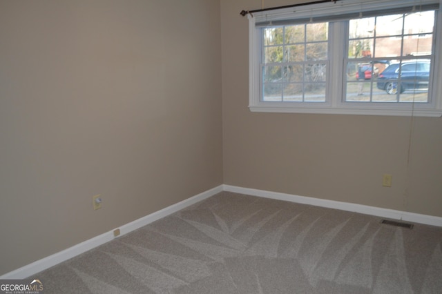 unfurnished room with carpet, visible vents, and baseboards