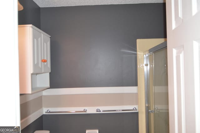 full bathroom with a shower stall and a textured ceiling