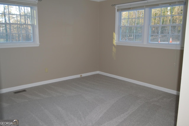 spare room featuring carpet floors, visible vents, and baseboards