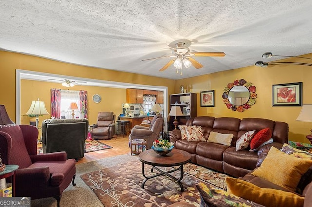 living room with a textured ceiling and ceiling fan