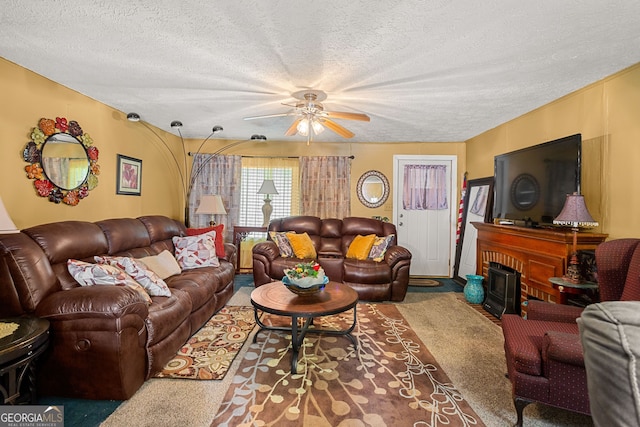 living room featuring ceiling fan, a fireplace, carpet, and a textured ceiling