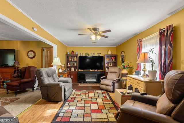 carpeted living room with ceiling fan, a fireplace, and a textured ceiling