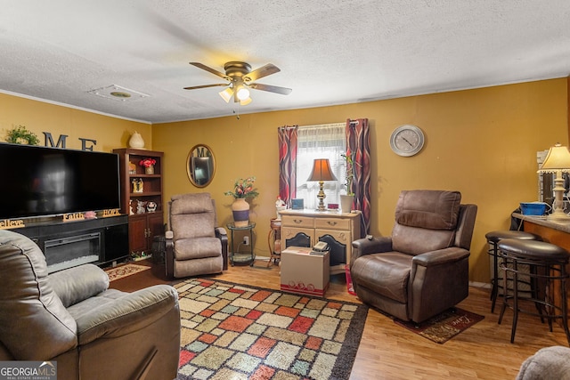 living room with wood-type flooring, ceiling fan, and a textured ceiling