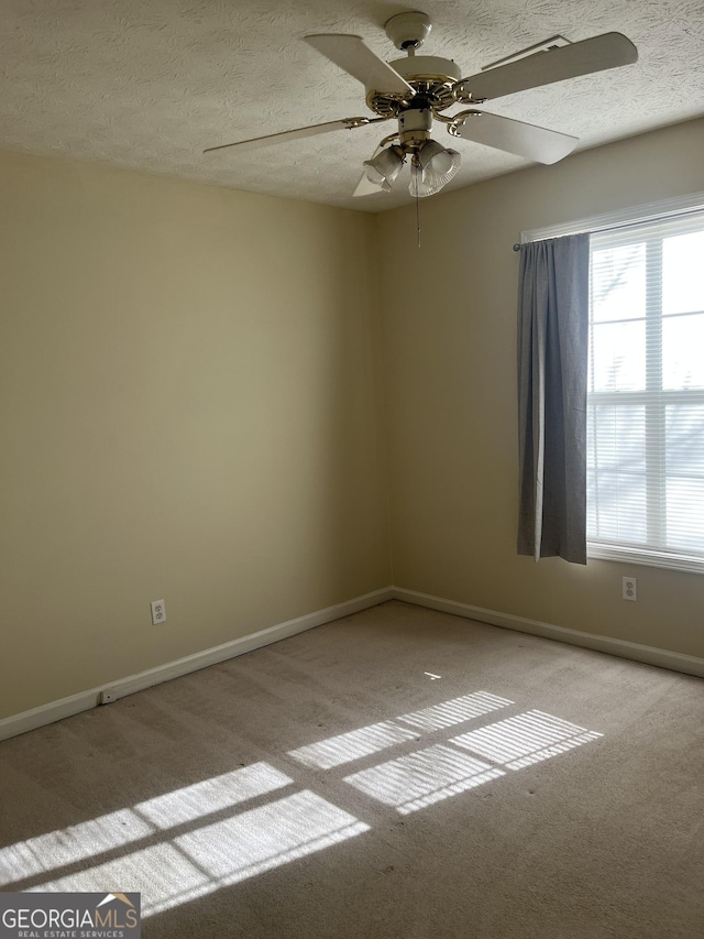 empty room featuring a textured ceiling, ceiling fan, and light colored carpet