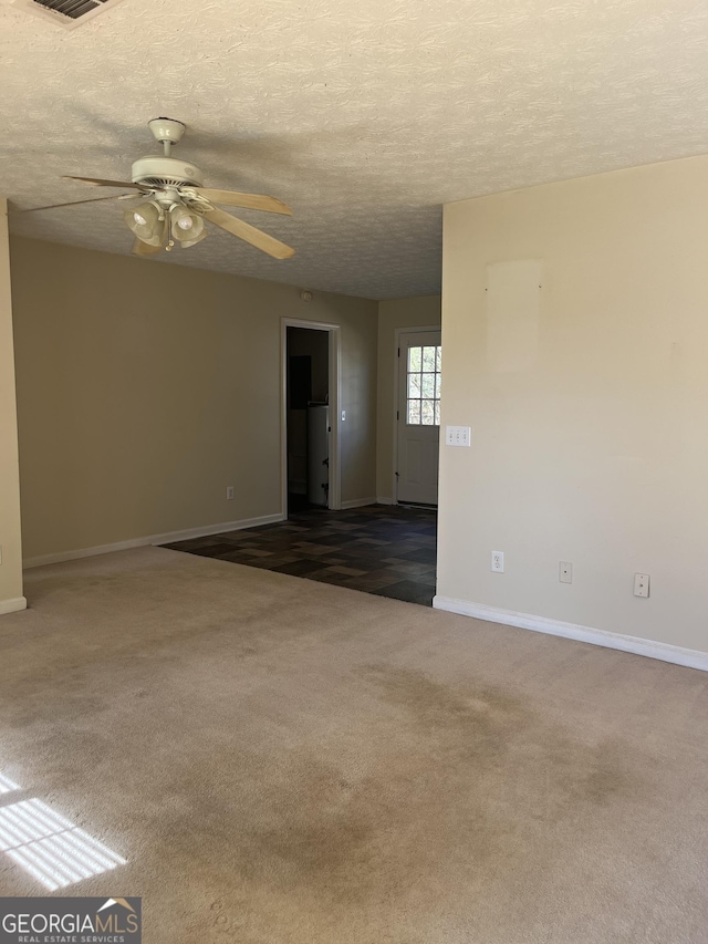 unfurnished room with a textured ceiling, ceiling fan, and dark carpet