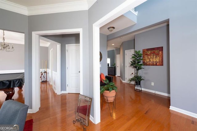 hall featuring a notable chandelier, crown molding, and wood-type flooring